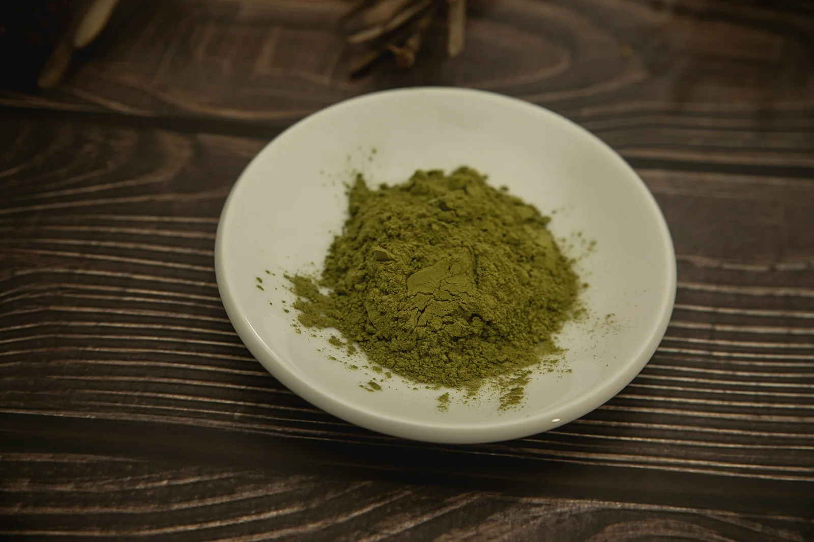 Moringa leaf powder on a white plate on a wooden table