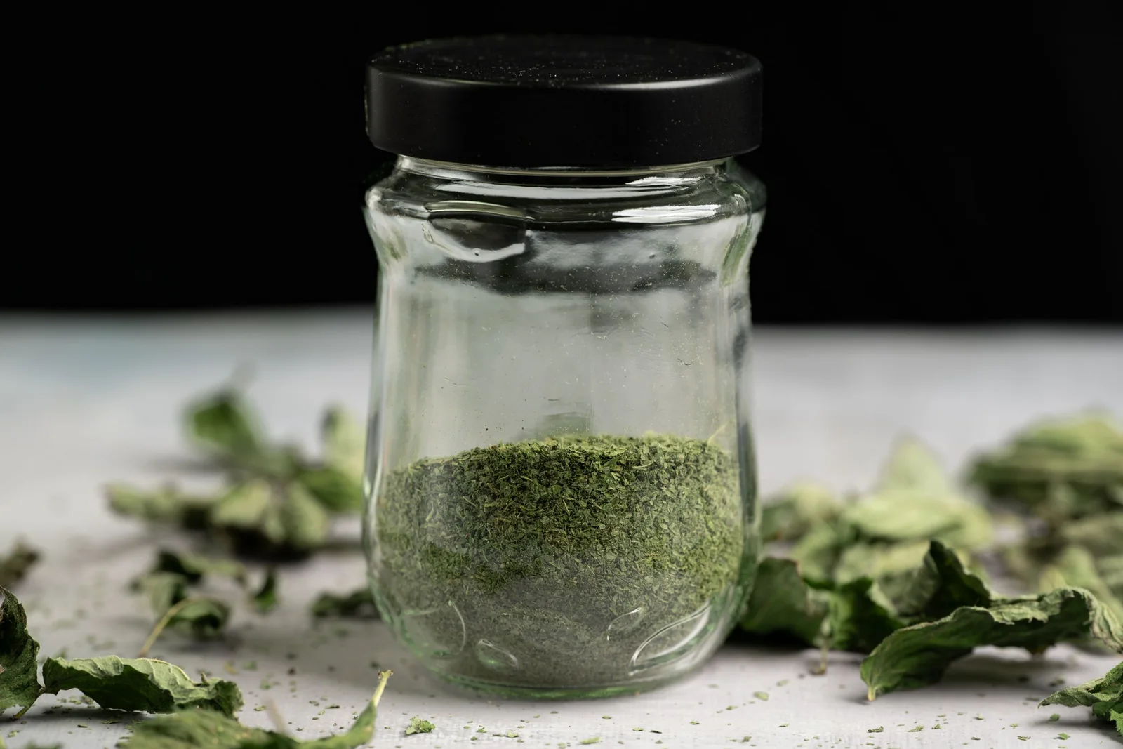 Glass sample jar of fine green powder